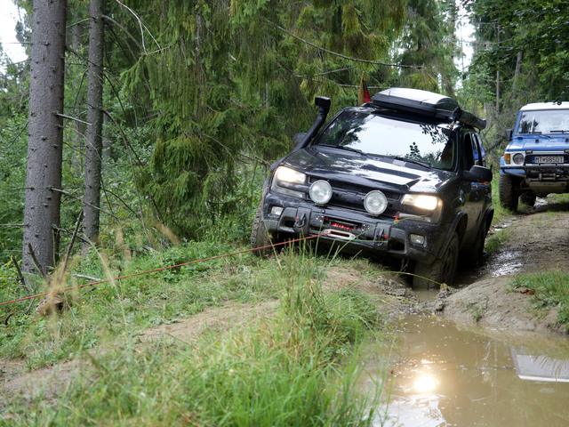 Visureigis važiuoja per gilią balą miško keliu